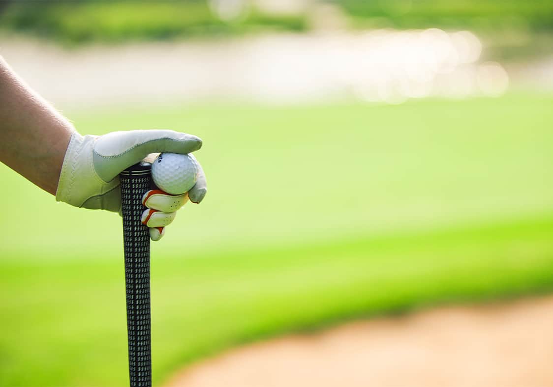 person holding a golf ball and club